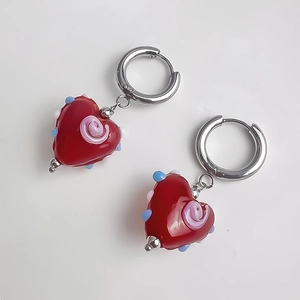 Détail de boucles d'oreilles créoles coeur rouge avec spirales colorées et métal argenté