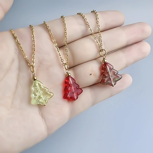Three colorful Christmas tree necklaces in green, red, and brown on gold chains
