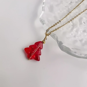 Detailed macro view of festive red glass Christmas tree pendant on a gold steel chain