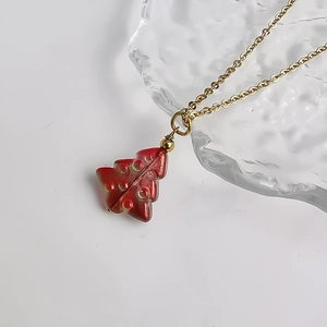 Macro shot of a red glass Christmas tree pendant with a fine gold stainless steel chain