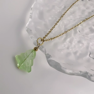 Macro detail of Christmas tree pendant with green glass texture and gold chain