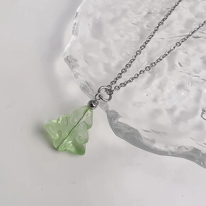 Close-up of translucent light green Christmas tree pendant with silver chain necklace