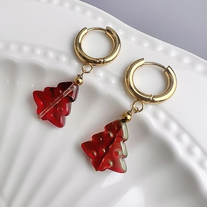 Macro de boucles d'oreilles sapin de Noël dorées avec résine rouge sur plateau céramique