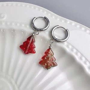 Détail de boucles d'oreilles sapin de Noël avec breloques rouges sur créoles en acier