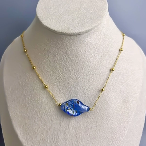Detail of 18K gold-plated titanium chain with blue painted glass pendant on a neck model