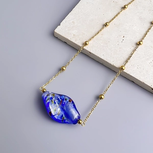 Macro detail of irregular deep blue art glass pendant on 18K gold plated steel chain