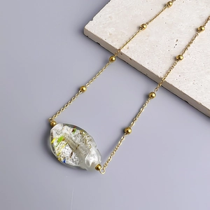 Detailed macro view of an irregular glass pendant on an 18K gold-plated bead necklace