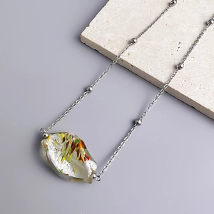 Detail of irregular glass pendant with colorful fibers and 18K gold-plated beads on necklace