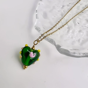 Detailopname van de groene glazen hartvormige ketting met kleurrijke 3D bloemaccenten