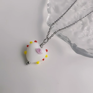 Detail van zoete hartvormige geglazuurde hanger met roze krullen en kleurrijke kralen