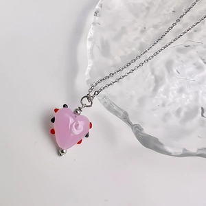 Detailopname van roze glazen hartvormige hanger met kleurrijke stippen op zilveren ketting