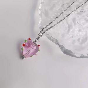 Detail van roze hartvormige hanger met roos en gekleurde stippen aan een zilveren ketting