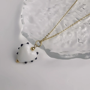 Gros plan d'un pendentif cœur en verre à pois noirs sur une chaîne dorée fine