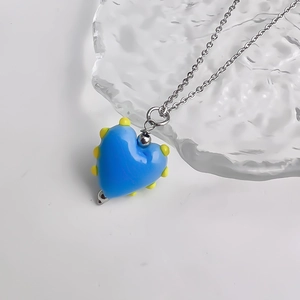 Vue macro d'un pendentif cœur en verre bleu avec points jaunes sur surface en verre
