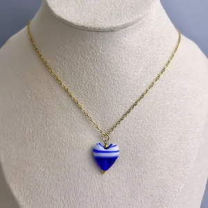 Détail du collier avec pendentif cœur en verre rayé bleu et blanc sur chaîne dorée