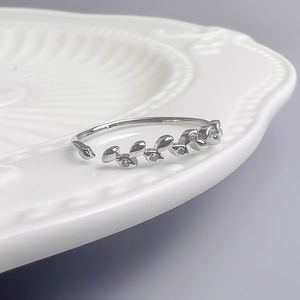Macro d'une bague feuilles de vigne argentée avec zircons sur une assiette blanche