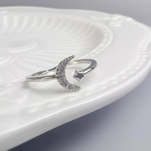 Gros plan d'une bague lune et étoile en argent avec zircons sur une assiette blanche