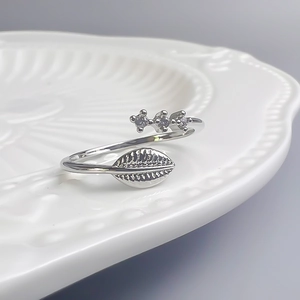 Gros plan détaillé d'une bague feuille en argent avec zircons sur une assiette blanche