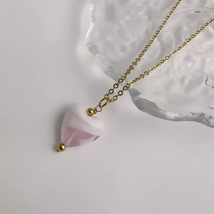 Détail du pendentif cœur en résine rose et blanc sur collier chaîne dorée