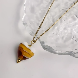 Gros plan d'un pendentif cœur avec texture ambre et chaîne en acier doré inoxydable