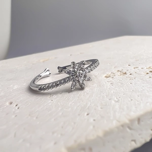 Bague étoile argentée minimaliste avec zircons sertis sur fond de pierre blanche