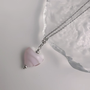 Détail du pendentif en forme de cœur avec texture marbrée rose sur chaîne argentée