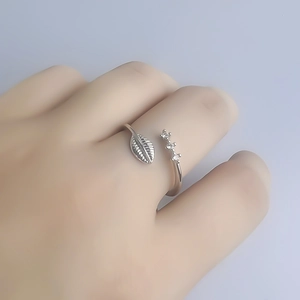Bague ajustable argentée au design de feuille et trois zircons, portée délicatement au doigt