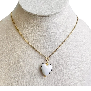 Collier cœur doré avec pendentif en verre blanc à pois sur présentoir