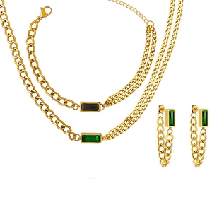 Detail view of double chain gold necklace and earrings with emerald zircon stones