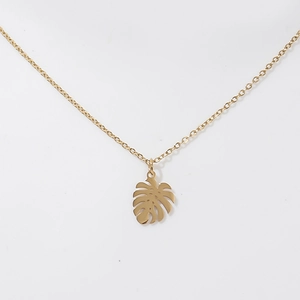 Macro detail of 18K gold monstera leaf pendant on a stainless steel necklace chain