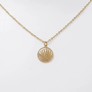 Macro shot of 18K gold palm leaf cutout pendant on a fine stainless steel chain