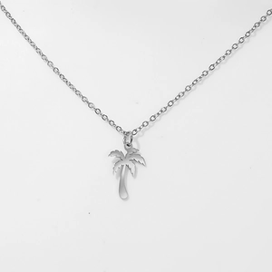 Close-up of minimalist hollow palm tree pendant on a thin silver stainless steel chain