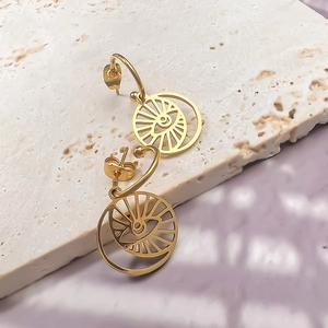 Macro detail of 18K gold-plated C-shaped earrings with hollow evil eye sun pendants