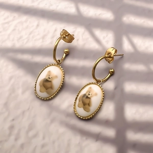 Boucles d'oreilles chic en titane doré avec pendentif ours ovale et bord perlé