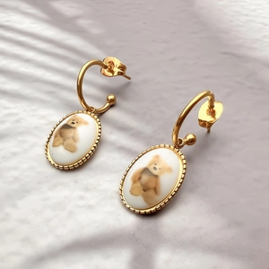 Élégantes boucles d'oreilles ovales dorées avec motifs ours en céramique et bordure perlée