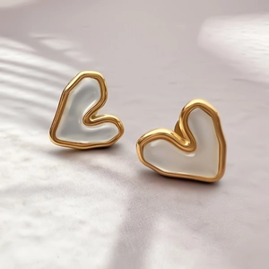 Detailed macro view of gold heart-shaped earrings with cat eye stones and soft shadows