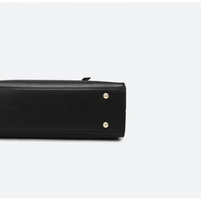 Detail shot of black lychee grain leather handbag base with gold protective metal studs