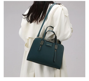 Detailed side view of dark green pebbled leather tote bag worn with a white trench coat