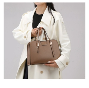 Brown litchi leather tote bag with gold hardware shown on white coat model