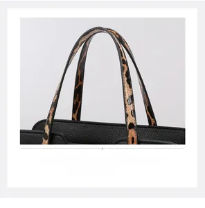 Close-up of black lychee grain leather handbag with leopard print handle details