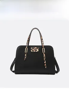 Detail of black pebbled leather handbag with leopard print accents and gold hardware