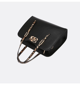 Detail view of black litchi leather tote with leopard print handles and gold buckles