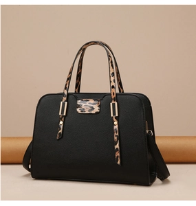 Detail of black pebbled faux leather tote with leopard print handles and gold hardware