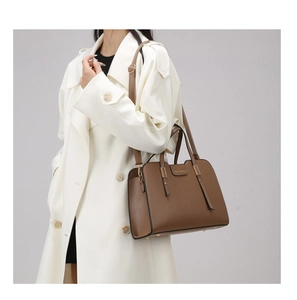 Detail of dark brown tote bag with leather texture, gold hardware and shoulder strap