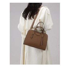 Brown grainy leather tote shown on model's shoulder highlighting size and elegant style