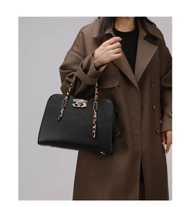 Detail of black tote bag with leopard print handles and protective gold metal feet
