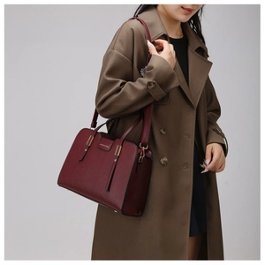 Detail of burgundy pebbled leather tote bag with gold buckle and fashion text engraving