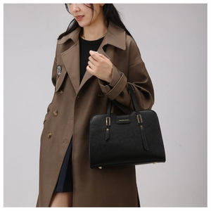 Close-up of black lychee grain leather handbag with gold metal hardware and brand logo