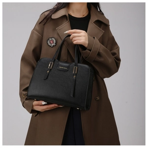 Detail of black pebbled leather tote bag with gold metal logo and sturdy handles