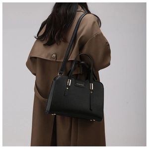 Close-up of black lychee grain leather tote bag with gold hardware worn on shoulder